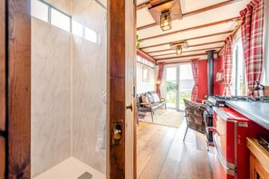 A kitchen with a red stove, wooden beams, and a view to the outside.