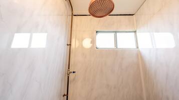 Een douche met een handdouche, een raam en een deur met een handdoekhouder.