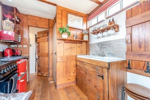A compact kitchen with wooden cabinets, a red stove, and a sink.