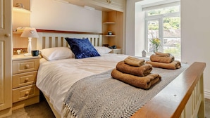 A bedroom with a bed, bedside tables, a lamp, a window with a view, and a towel rack. - 3 Bed in Looe (oc-92273) (Polperro)