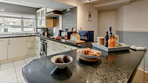 A modern kitchen with a large island, stainless steel appliances, and a view of the outside. - 3 Bed in Looe (oc-92273) (Polperro)