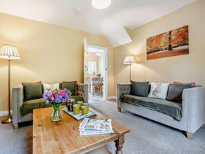 Ein Wohnzimmer mit zwei Sofas, einem Couchtisch mit Blumenvase und einem Gemälde an der Wand.