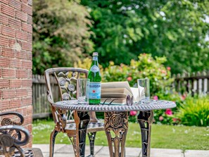 A table with a bottle of water, glasses, and a book, set against a garden backdrop. - 2 Bed in Alford (oc-92252) (Rigsby)