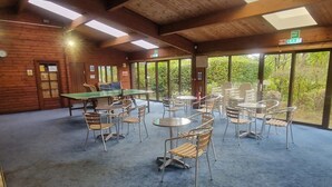 A covered outdoor area with tables and chairs, a ping pong table, and a wooden wall with windows. - 2 Bed in Ambleside (oc-92240) (Grasmere)