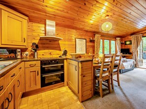 A wooden cabin interior with a kitchen, dining area, and a bed.