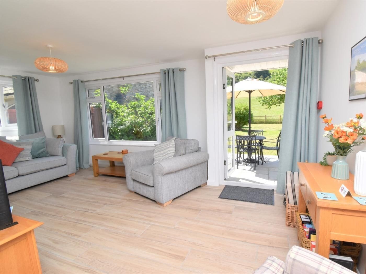 Sala de estar com sofá, uma mesa e vista para o jardim através de uma porta de vidro.