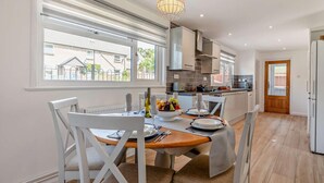 A modern kitchen with a dining area, large windows, and a hanging light fixture. - 3 Bed in Wareham (oc-92328) (West Lulworth)