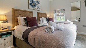 Ett hotellrum med en stor säng, ett sängbord med en lampa, ett litet bord, ett fönster med utsikt och en spegel.