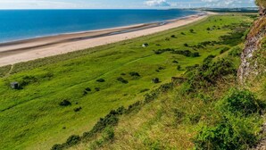 Eine Küstenlandschaft mit Strand, Wiesen und einer Klippe.