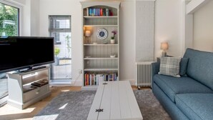A living room with a flat-screen TV, a bookshelf, a sofa, and a coffee table. - 1 Bed in Norwich (oc-92295) (Strumpshaw)