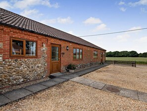 A brick house with a stone foundation, a tiled roof, and a gravel driveway. - 2 Bed in Dereham (oc-92392) (Horningtoft)