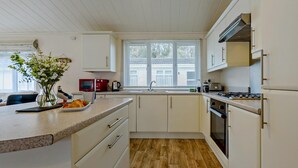 Una cocina con armarios blancos, encimera de madera, una ventana y una estufa.
