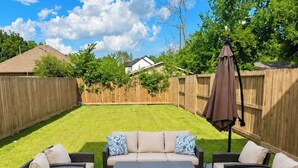 Un jardin avec un ensemble de mobilier de patio, une clôture en bois et une pelouse.