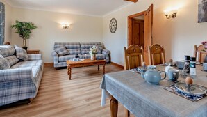 Ein gemütliches Wohnzimmer mit einer Couch, einem Holztisch und einem Esstisch, gedeckt mit Tee und Kaffee.