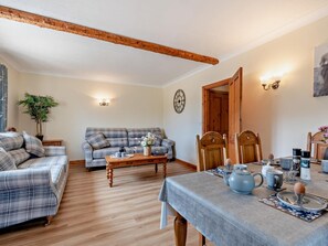 Ein gemütliches Wohnzimmer mit einer Couch, einem Holztisch und einem Esstisch, gedeckt mit Tee und Kaffee.