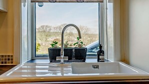 Ein Badezimmer mit Fenster, Waschbecken, Wasserhahn und einer Handseifenflasche.