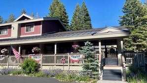 A two-story building with a covered porch, a flag, and a 'No Parking' sign. - Cozy Village Condo | Hot Tub, Sauna, Fireplace (Mammoth Lakes)