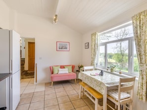 A room with a kitchen area, a dining table with chairs, a pink sofa, and a window with curtains. - 2 Bed in Buxton (oc-91974) (Wormhill)