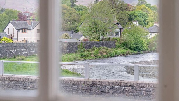 A river with houses on one side and a stone wall on the other. - 2 Bed in Keswick (oc-92145) (Keswick)