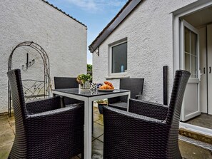 A patio with wicker furniture, a table with a plate of food, and a window. - 2 Bed in Keswick (oc-92145) (Keswick)
