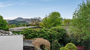 A residential area with a stone wall, a wooden shed, and a house with a sloped roof. - 2 Bed in Keswick (oc-92145) (Keswick)