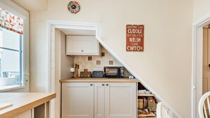 Eine kleine Küche mit Mikrowelle, Toaster und einer Uhr an der Wand.
