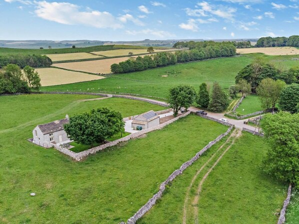 Une propriété rurale avec des murs en pierre, une petite maison et des champs.