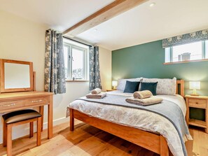 Une chambre à coucher comprenant un lit, un bureau, une chaise, une commode et une fenêtre avec des rideaux.
