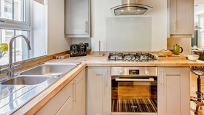 Una cocina moderna con horno empotrado, estufa a gas, tostadora y pileta.