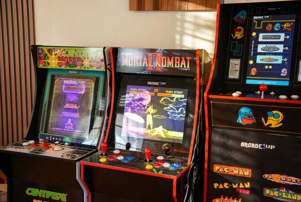 Deux bornes d’arcade, l’une pour le jeu Centypede et l’autre pour Mortal Kombat, avec des graphismes colorés et des titres de jeux attrayants.