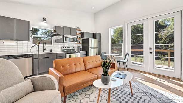 A modern kitchen with a sofa, dining table, and a view of the outdoors. - Sleeps 12 / Two Homes For Large Groups
Game Day Get-away and
Clear Creek Retreat (Fayetteville)