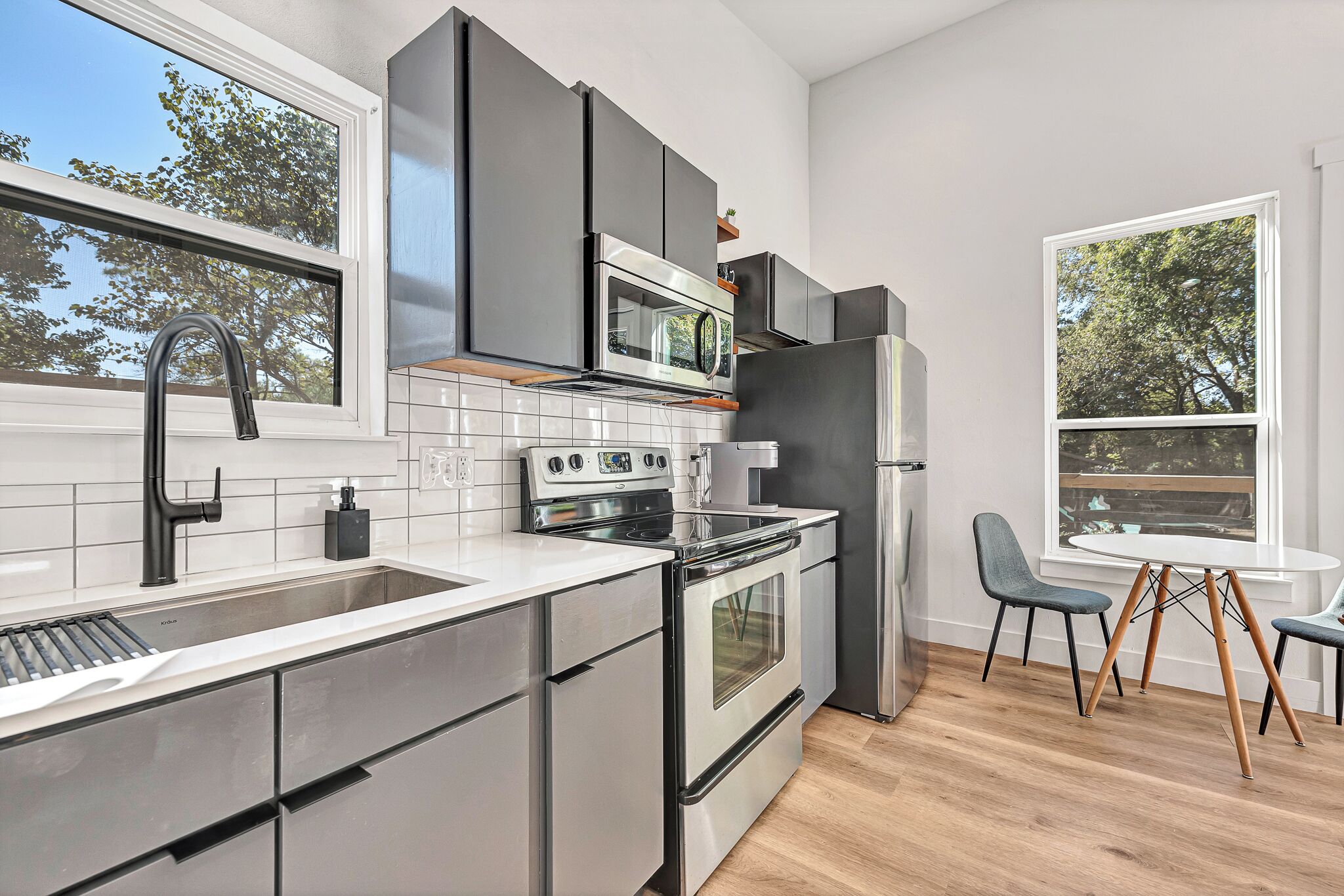 Una cocina moderna con electrodomésticos de acero inoxidable, un ventanal grande y un comedor con una mesa redonda y sillas.