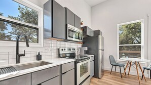 A modern kitchen with stainless steel appliances, a large window, and a dining area with a round table and chairs. - Sleeps 12 / Two Homes For Large Groups
Game Day Get-away and
Clear Creek Retreat (Fayetteville)
