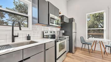 Una cocina moderna con electrodomésticos de acero inoxidable, un ventanal grande y un comedor con una mesa redonda y sillas.