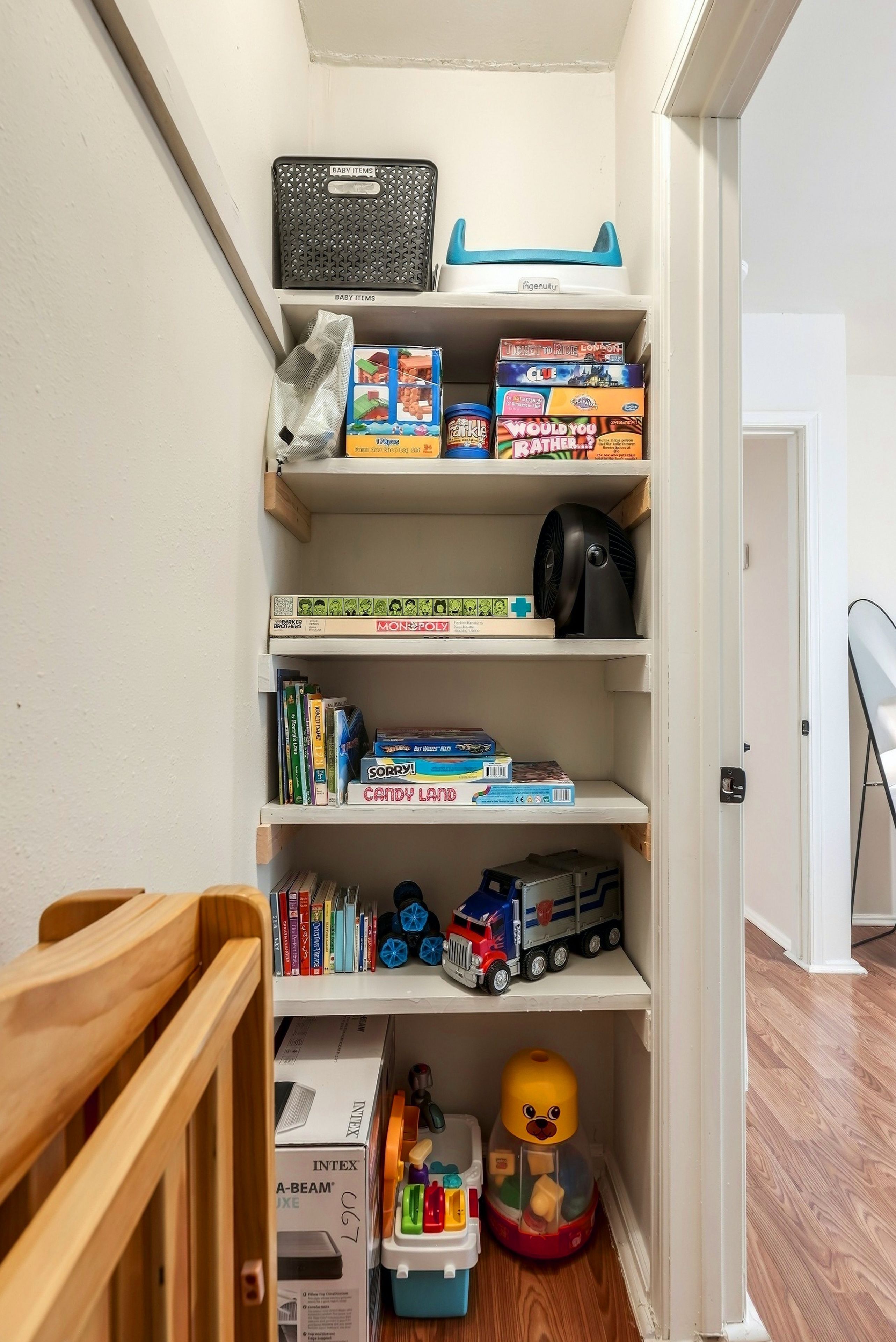 Un depósito de almacenamiento con estanterías que contienen artículos para bebés, juegos de mesa y un camión de juguete.