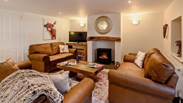 A living room with leather sofas, a fireplace, a television, and a mounted mirror. - 4 Bed in Alston (oc-92351) (Alston)