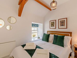 Une chambre avec un lit, deux miroirs fixés au mur, une fenêtre donnant sur un paysage agréable et deux tableaux encadrés.