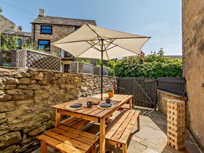 Une terrasse en bois avec une table et des bancs, un mur en pierre et une clôture en bois.