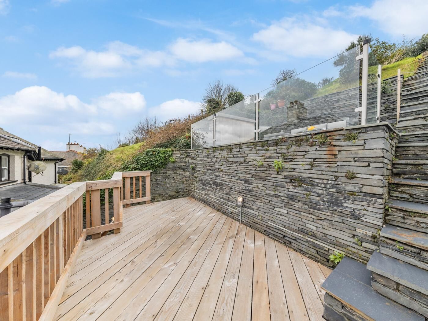 Une terrasse en bois avec des murs en pierre, une balustrade en bois et un ciel dégagé.