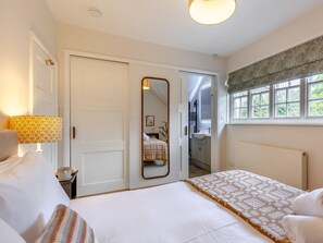 Ein Hotelzimmer mit einem Bett, einer Nachttischlampe, einem Fenster mit Blick und einer Tür zu einem Badezimmer.