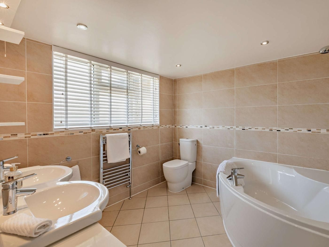 Een moderne badkamer met een groot bad, een wastafel en een toilet.