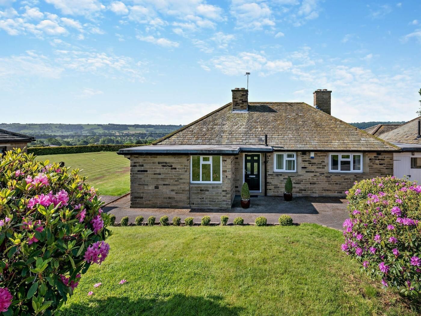 A stone house with a front door, windows, and a chimney.