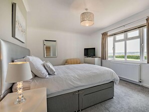 A bedroom with a bed, a television, a lamp, a window with curtains, and a view of the outdoors. - 2 Bed in Otley (oc-92378) (Leathley)
