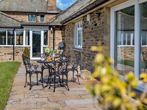 A patio with a table and chairs, a potted plant, and a brick wall. - 2 Bed in Otley (oc-92378) (Leathley)