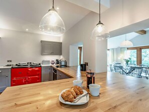 Een moderne keuken met houten aanrecht, rode apparaten en een ontbijtarrangement met croissants.