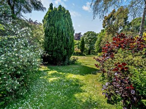 Un jardin où l’on trouve une grande variété d’arbres et de plantes à fleurs.