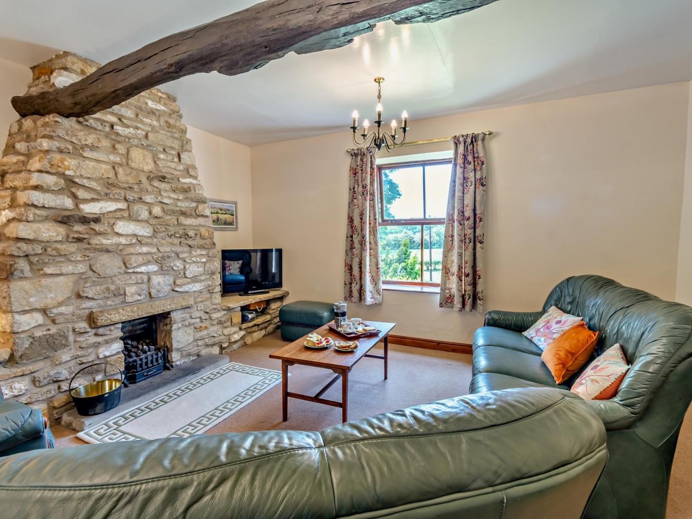 A living room with a stone fireplace, leather sofa, and a television.