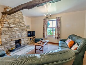 A living room with a stone fireplace, leather sofa, and a television. - 3 Bed in Pickering (oc-92356) (Cropton)
