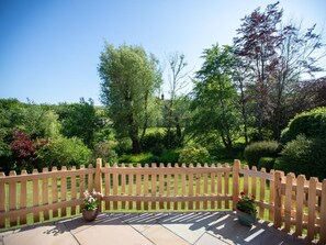 A wooden deck with a picket fence, potted plants, and a view of a lush garden. - 3 Bed in Dorchester (oc-92343) (Higher Wraxall)