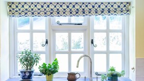 Eine Küche mit Fenster, Spüle und Topfpflanzen.